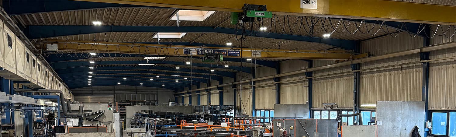 Innenansicht einer Produktionshalle mit Laufkrananlage von Stahl. Die Anlage ist für Lasten bis 3200 kg ausgelegt und beleuchtet den Arbeitsbereich optimal.