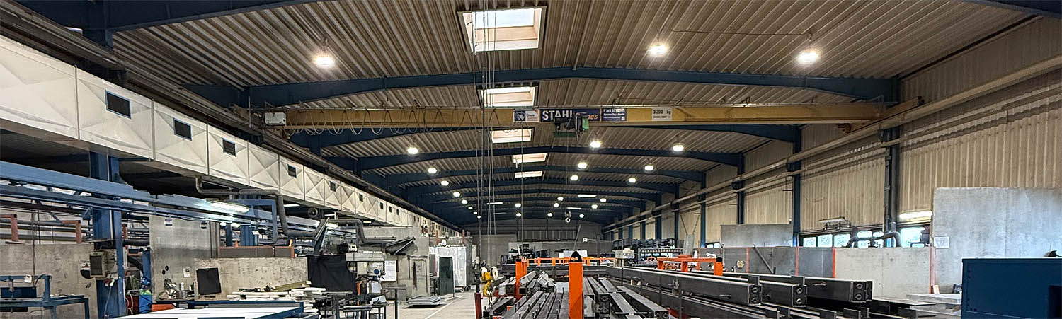 Innenansicht einer Produktionshalle mit Stahlträgern und Krananlage. Optimiert für Industrie und Fertigung.